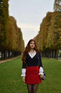 Portrait of young woman standing against plants