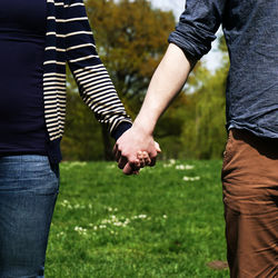 Midsection of young couple holding hands in park