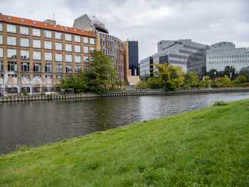 Buildings by river against sky