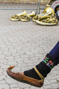 Low section of woman wearing shoe on footpath