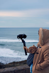 Man photographing at beach against sky