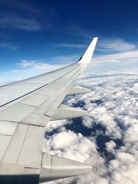 Cropped image of aircraft wing flying against sky