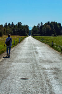 Rear view of man walking on road against sky