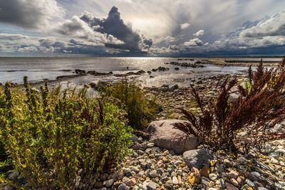 View of calm beach against cloudy sky