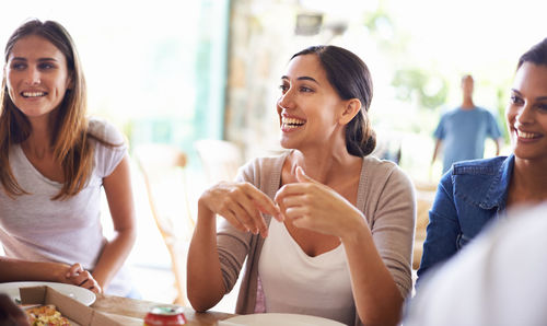 Smiling friends using smart phone while sitting at home