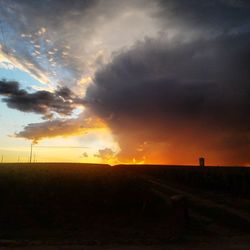 Scenic view of silhouette field against sky during sunset