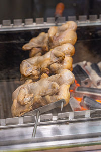 Grilling chicken legs on charcoal stove in commercial kitchen