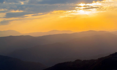 Scenic view of silhouette mountains against orange sky