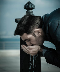Close-up of young man drinking water from fountain