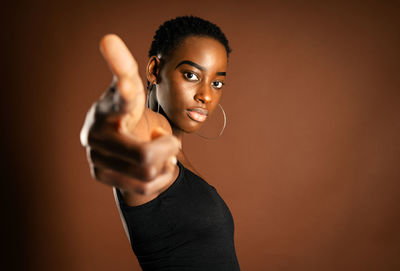 Portrait of young woman standing against black background