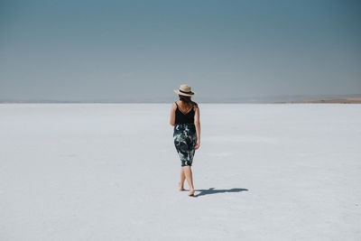 Woman standing by sea against clear sky