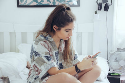 Young woman using mobile phone at home