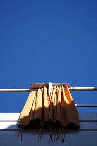  minimal and graphic low angle closeup of curtains hanging against clear blue sky under the sun.