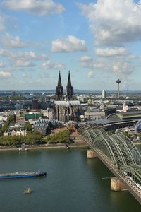 Bridge over river by buildings in city against sky