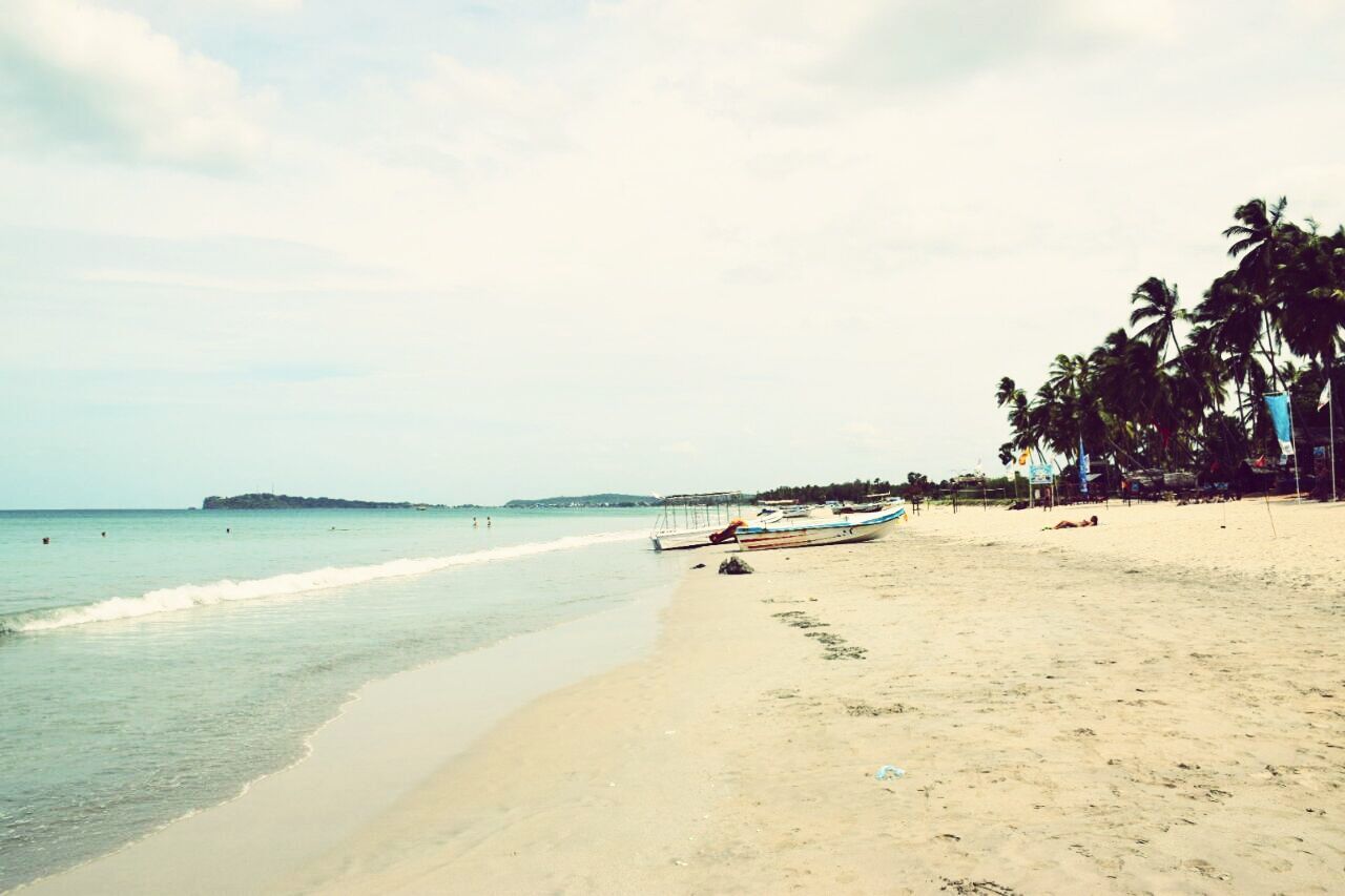 beach, sea, sand, water, shore, sky, horizon over water, boat, mode of transport, tranquility, tranquil scene, coastline, scenics, nature, beauty in nature, vacations, day, cloud - sky, outdoors, tourism, idyllic, cloud, travel destinations, blue