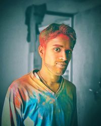 Portrait of young man with powder paint standing at home