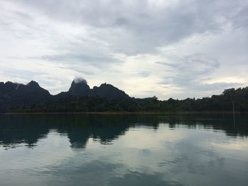 Scenic view of lake and mountains against cloudy sky