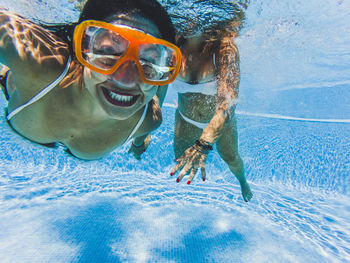 Portrait of happy woman with female friend swimming in pool