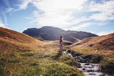 Woman standing on mountain against sky