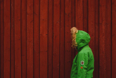 Man wearing hood while standing by fence