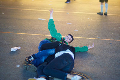 Drunk men lying on road at amusement park during night