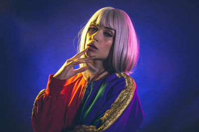 Portrait of young woman standing against blue background