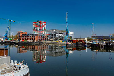 Reflection of buildings in water against clear blue sky