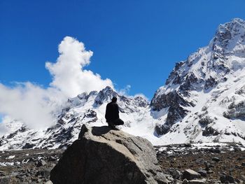 Person on rock against snowcapped mountain