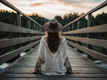 Rear view of woman sitting on boardwalk