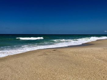 Scenic view of beach against clear blue sky