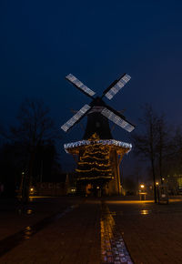 Illuminated traditional windmill against sky at night