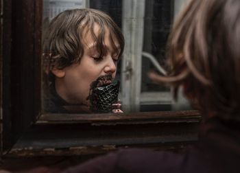 Portrait of young woman looking through window