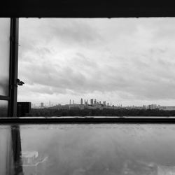 View of buildings by river against cloudy sky