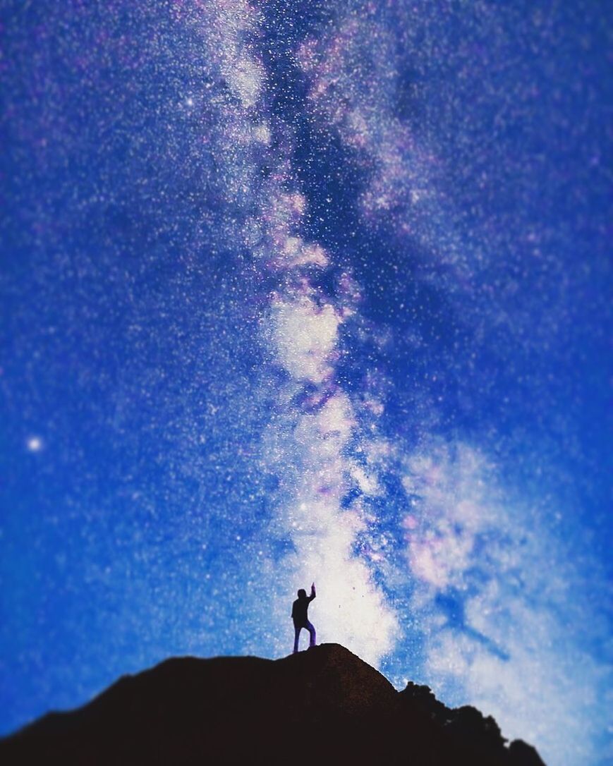 sky, silhouette, one person, leisure activity, standing, real people, nature, beauty in nature, lifestyles, scenics - nature, cloud - sky, land, men, night, star - space, tranquil scene, tranquility, low angle view, outdoors, astronomy, milky way, human arm, arms raised