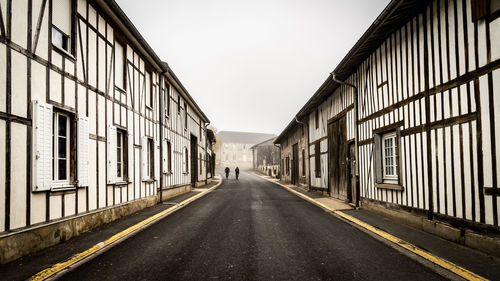 Empty road amidst buildings against clear sky