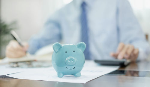 Midsection of businessman putting coin in piggy bank
