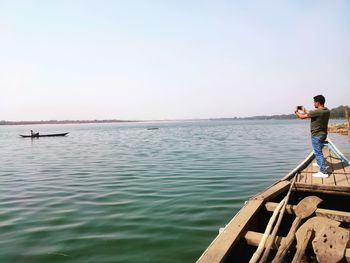 Rear view of men standing on sea against sky