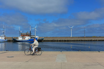 Man riding bicycle on shore against sky