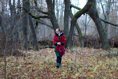 Full length portrait of smiling girl standing in forest during winter