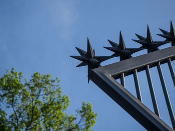 Low angle view of spiked stars on metal fence against clear blue sky