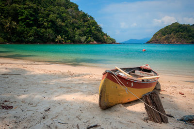 Boat moored on beach against sky