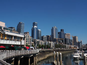 Reflection of buildings in city against clear blue sky