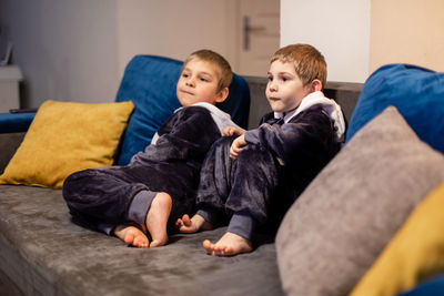 Friends watching movie while sitting on sofa at home