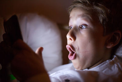 Shocked boy using smart phone in darkroom