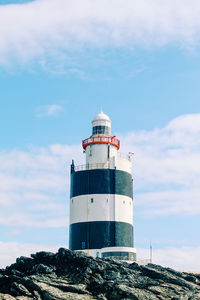 Low angle view of lighthouse by building against sky