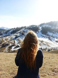 Rear view of woman standing in front of snowcapped mountains