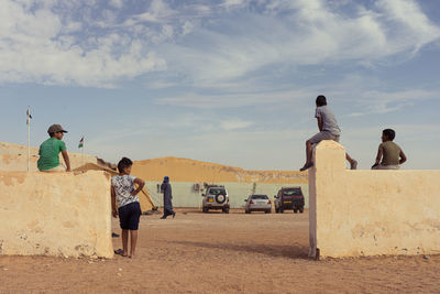 Rear view of people on road against sky