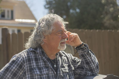 Senior man long gray hair against fence