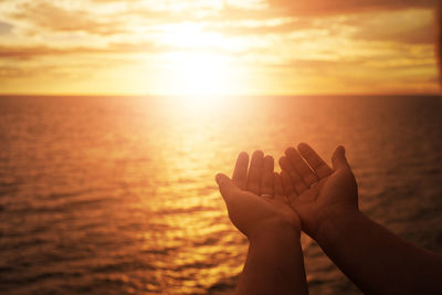 Cropped image of woman with cupped hands against sea