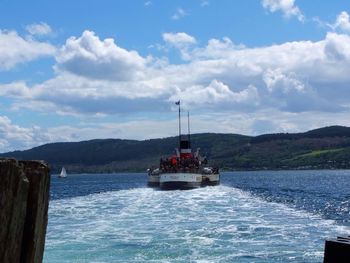 Boats in sea against cloudy sky